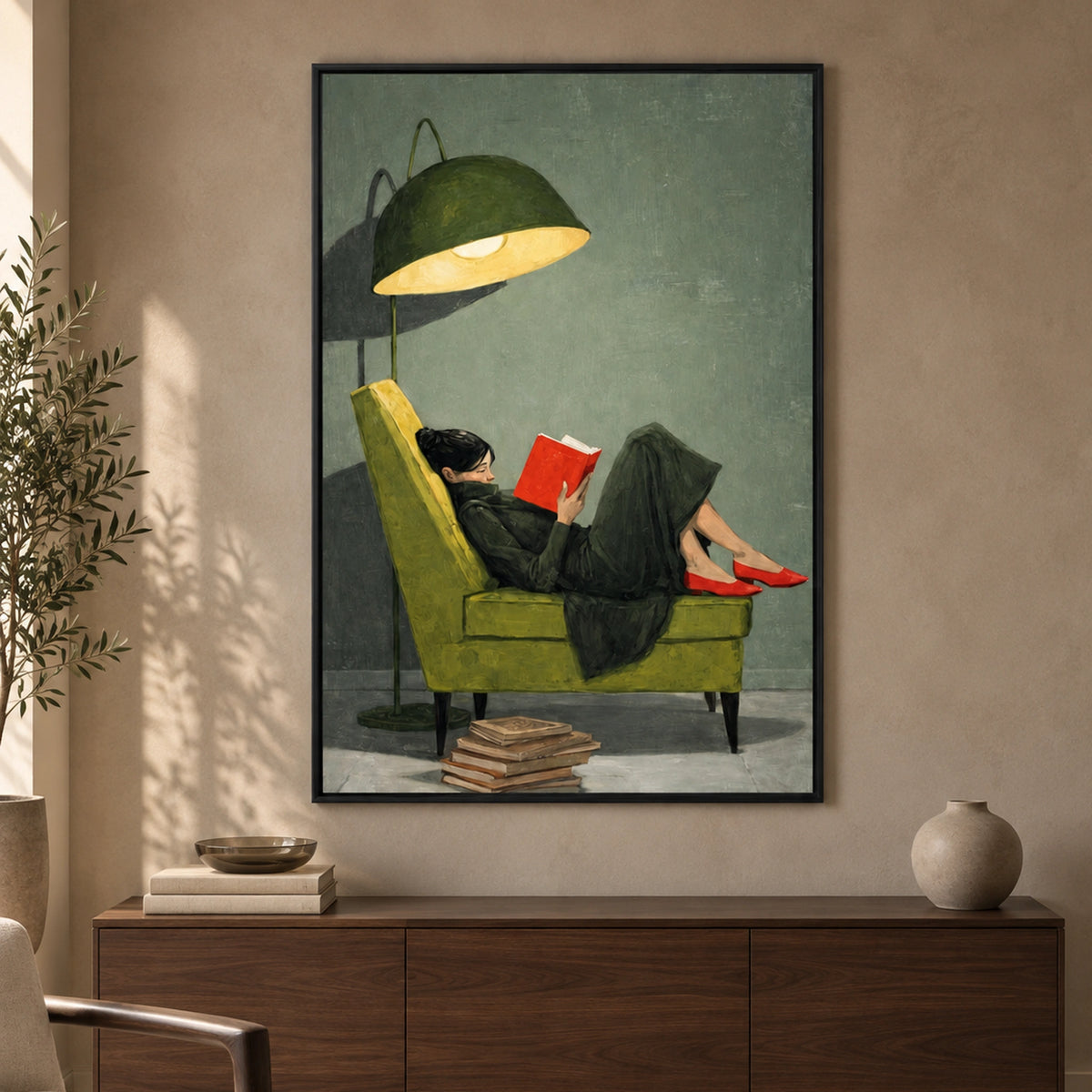 The Quiet Chapter in a thin black wooden frame above a walnut sideboard, depicting a woman reading in an olive-green chair.