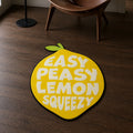 Lemon Squeezy die-cut rug — EASY PEASY LEMON SQUEEZY in cream lettering inside a yellow lemon with a green leaf, cut to the fruit shape with black edge binding