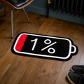 Low Battery die-cut rug — black battery icon reading 1% with a red sliver of charge, cut to the battery shape with black edge binding