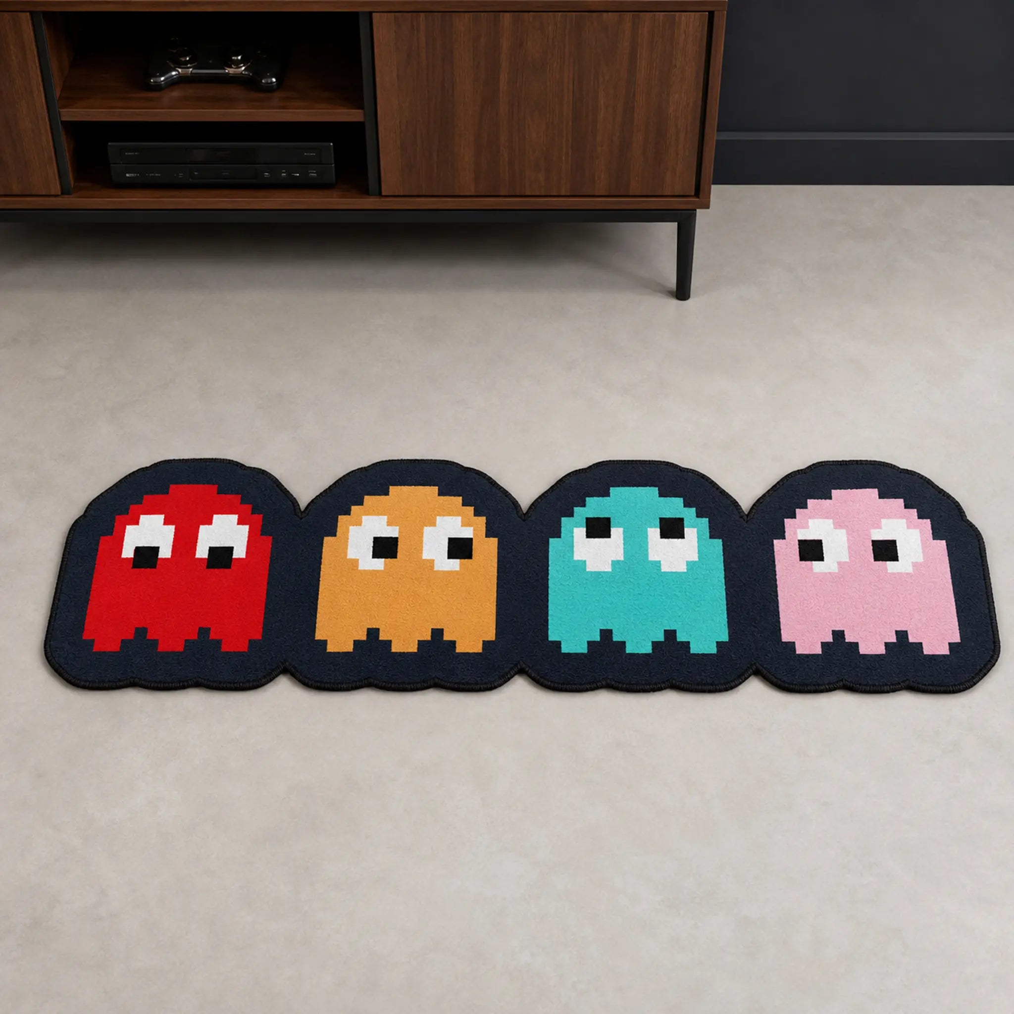 Pac-Man Ghost Squad die-cut rug — four pixel ghosts in red, orange, cyan and pink on black, cut to shape as a long runner with black edge binding