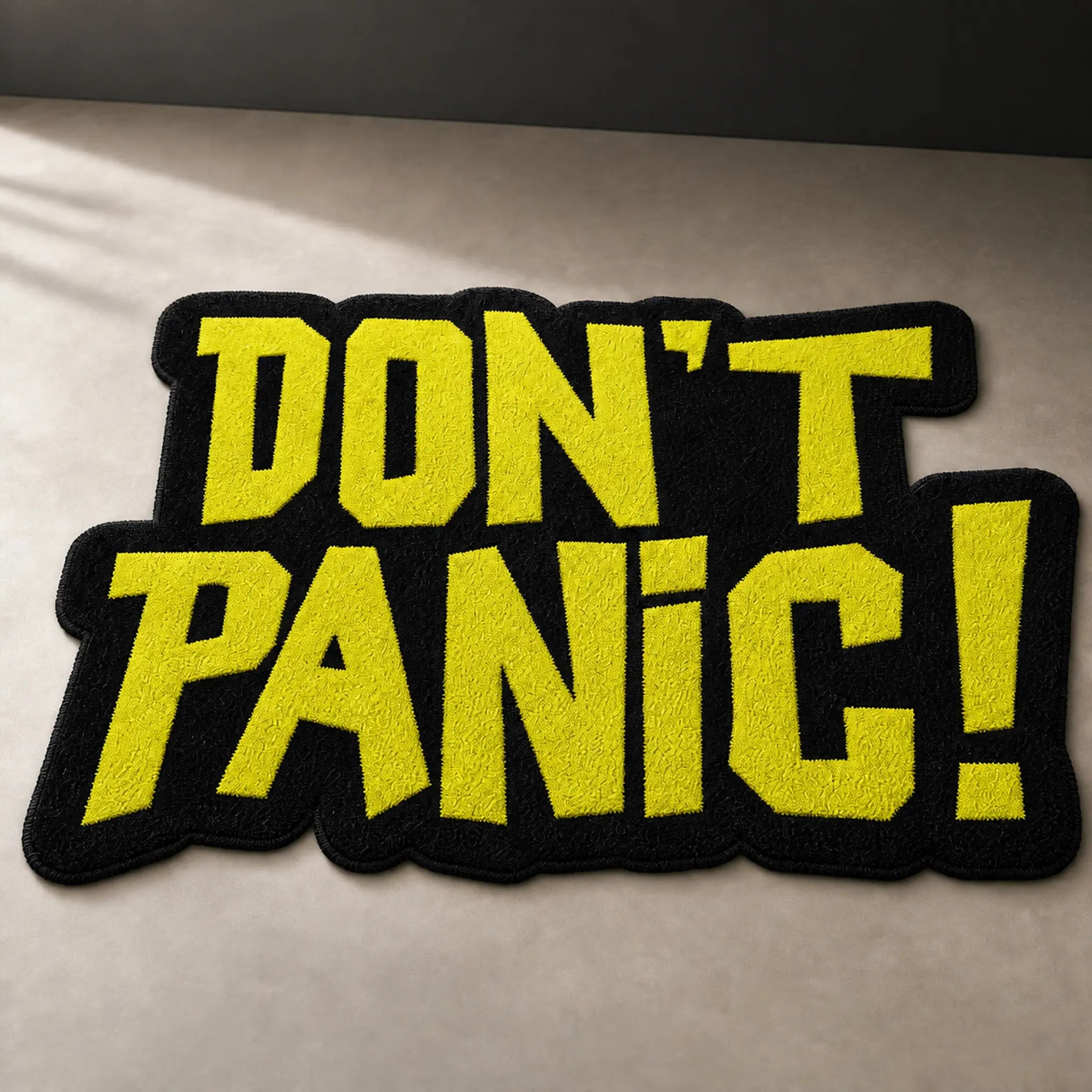DON'T PANIC die-cut rug — yellow lettering on black faux fur, cut to the shape of the words with black edge binding