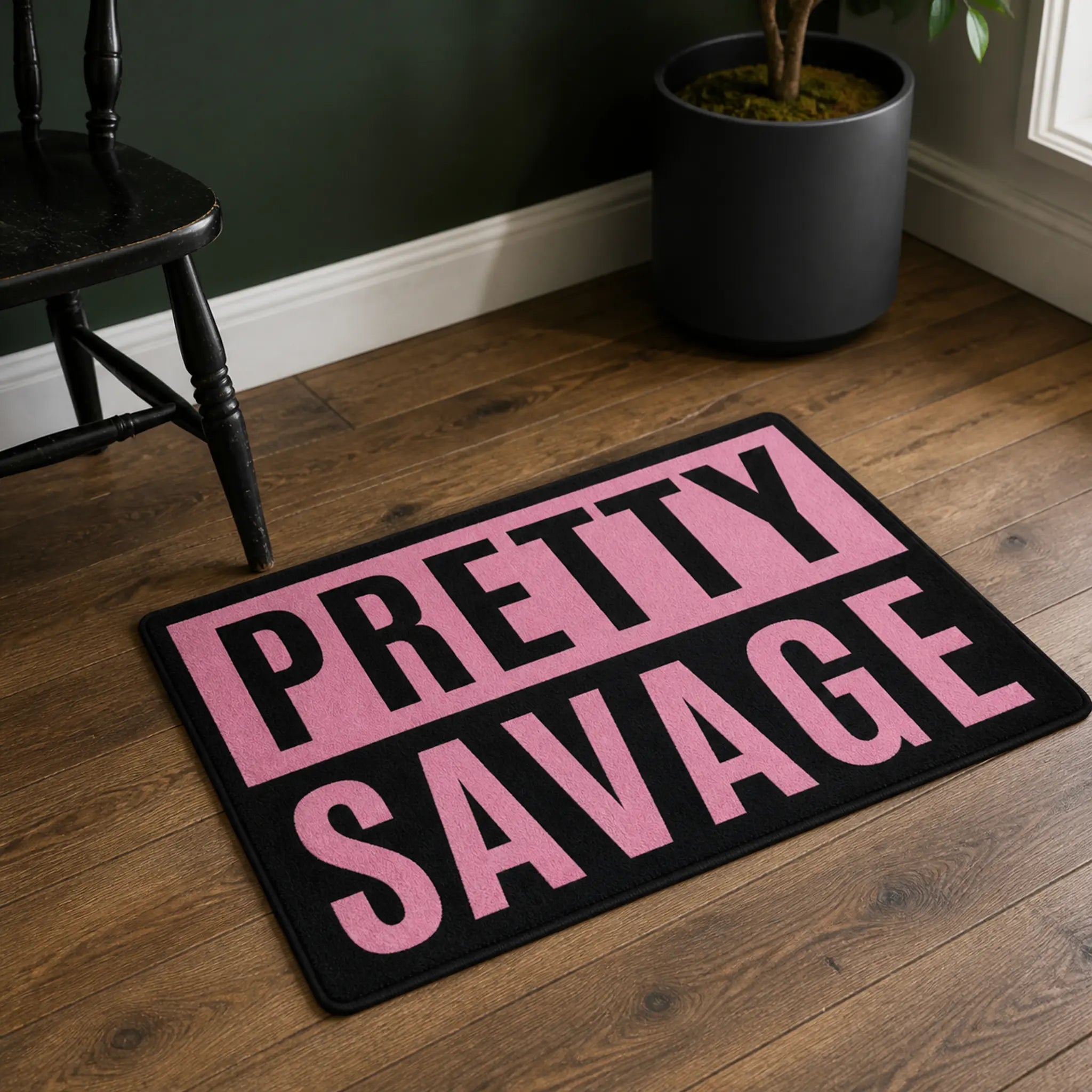 Pretty Savage rug — PRETTY SAVAGE in bold pink type on a black rectangular faux fur rug with black edge binding