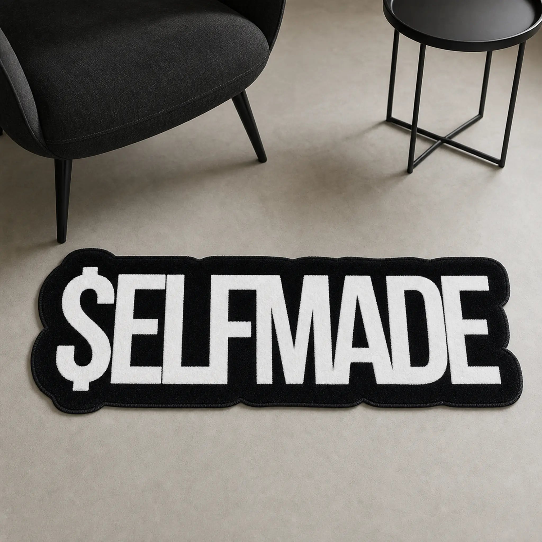 Self-Made Hustle die-cut rug — $ELFMADE in heavy white block letters on black, cut to the shape of the word with black edge binding