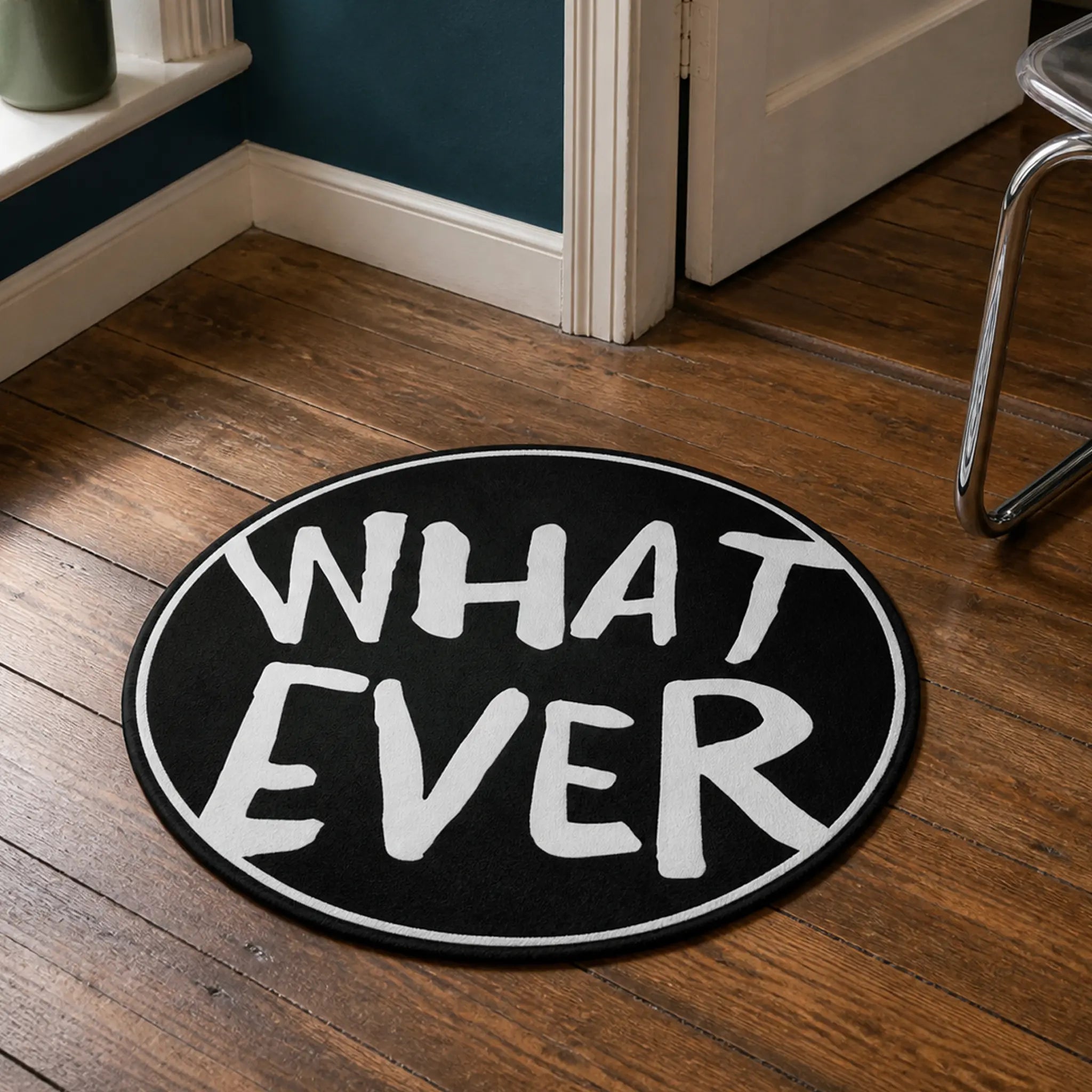 Whatever die-cut rug — WHAT EVER hand-lettered in white brush caps on a black circle with a thin white ring, cut to the round with black edge binding