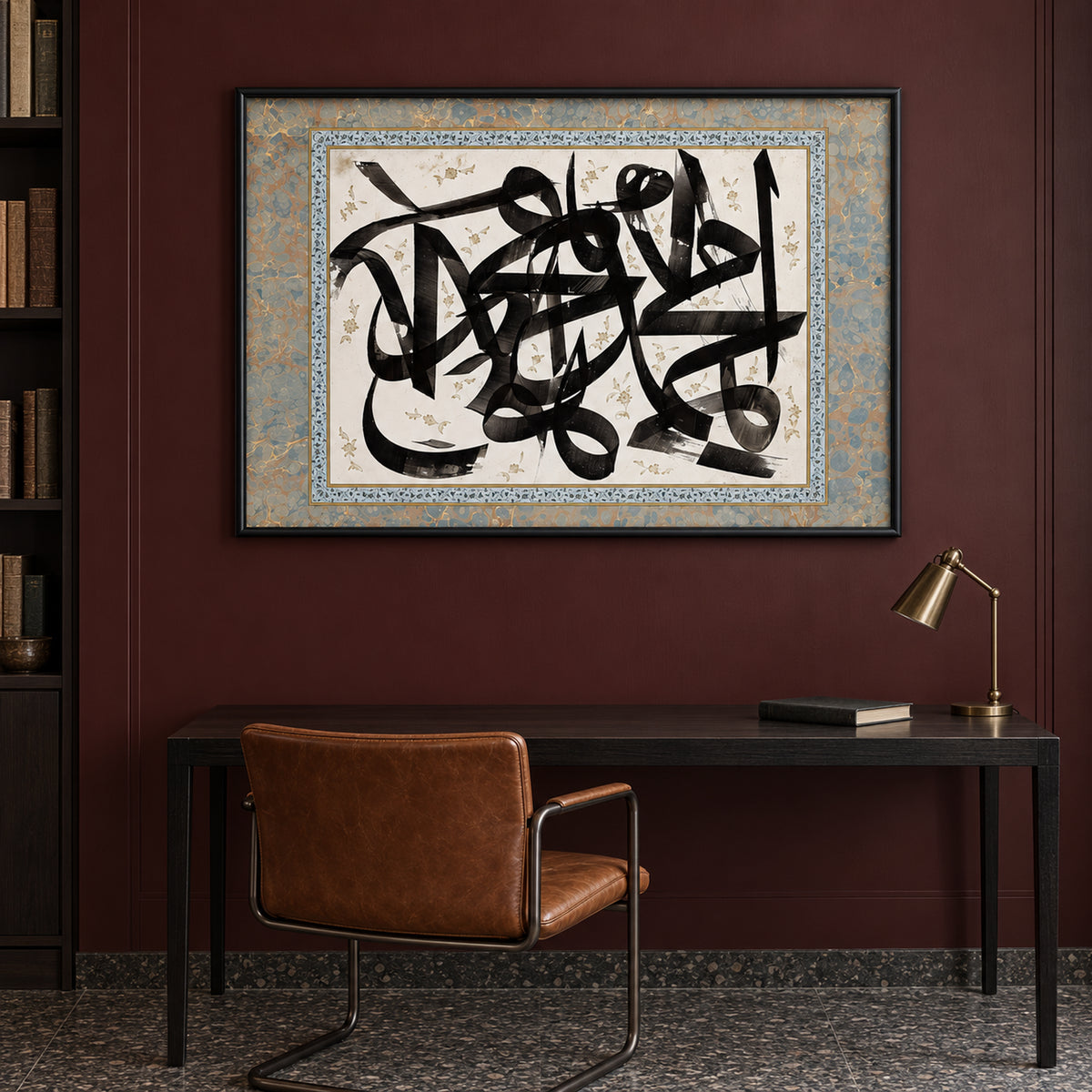Front view of Ink & Ivory: black Arabic calligraphy on ivory with a blue-grey and gold-toned border, in a black frame above a dark desk.