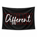 Black Think Different wall tapestry with red outline lettering and white handwritten script.